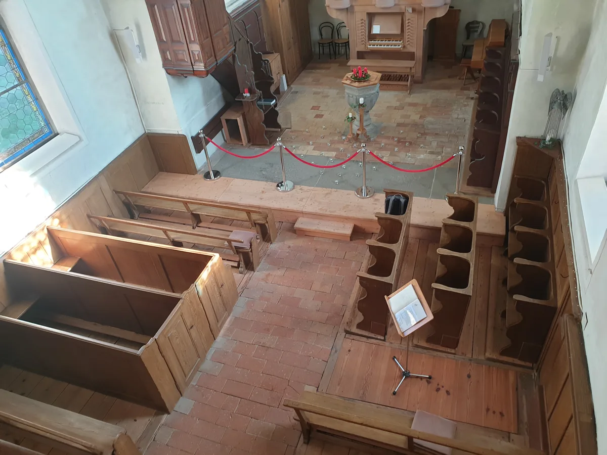 Man sieht eine Kirche. Es fehlt die Hälfte der Bänke, und auch sonst ist sie recht leer.
